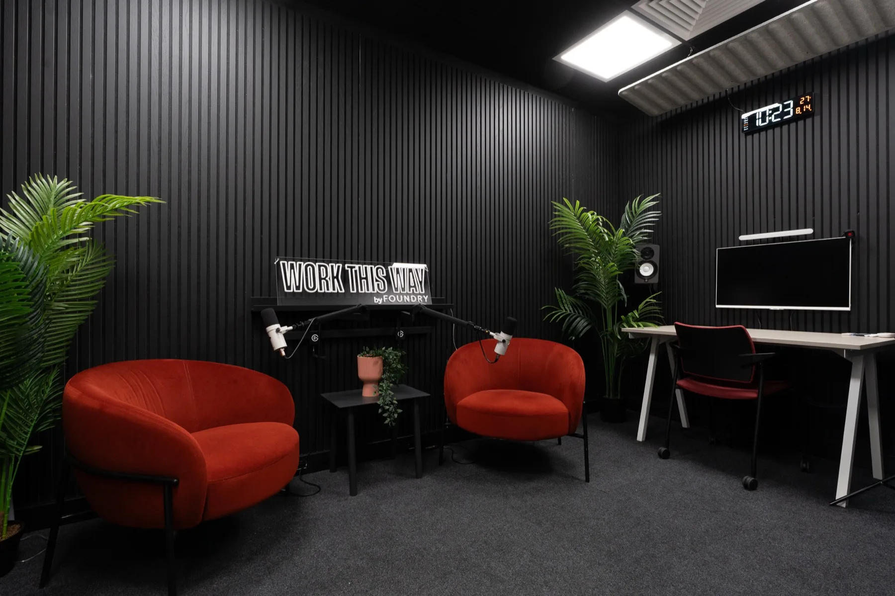 The little one: two armchairs with boom microphones, and the studio screen on a desk beyond